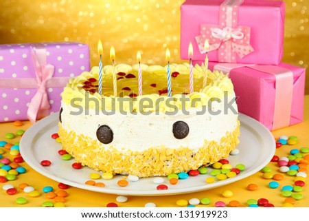 Happy birthday cake and gifts, on yellow background
