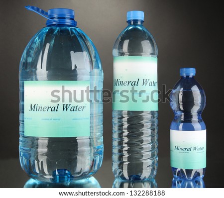 Different water bottles with label on grey background