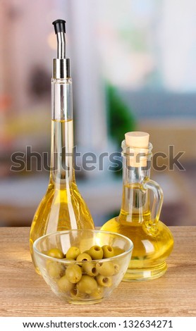 Different types of oil with olives on table in kitchen
