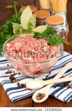 Bowl of raw ground meat with spices on wooden table