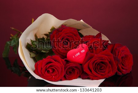 Beautiful bouquet of red roses with valentine on red background