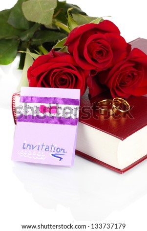 Wedding rings with roses and greeting card on bible isolated on white
