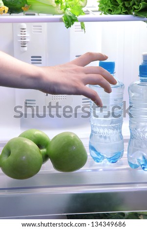 Woman's hand reaching out for food from the refrigerator, close up