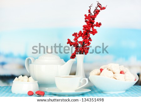 Beautiful white dinner service with an air meringues on blue tablecloth on natural background