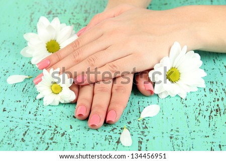 Woman hands with pink manicure and flowers, on color background