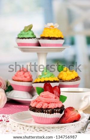 Beautiful strawberry cupcakes on dining table on room background