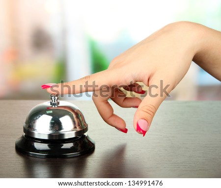 Female hand ringing in service bell on bright background