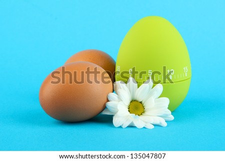 Green egg timer and eggs, on color background