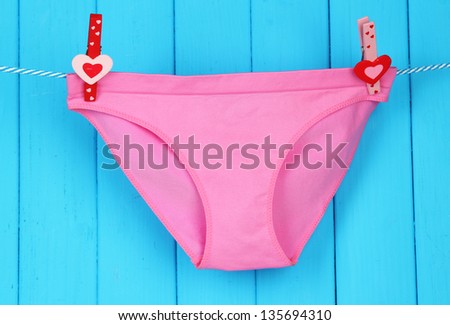 Womans panties hanging on a clothesline, on blue wooden background