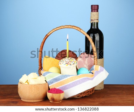 Easter basket: Conceptual photo of traditional easter food in wicker basket, on wooden table on color background