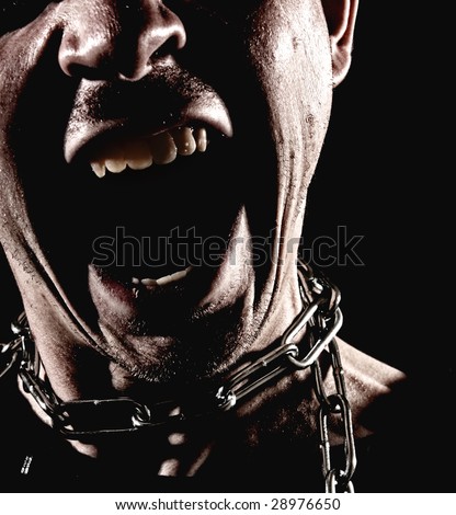 Closeup of a man wearing a chain around his neck with his mouth wide open in a dramatic scream. High contrast on black background