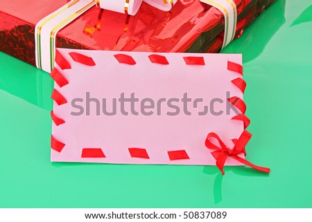 cardboard tags with red ribbon bow and gift box   on green background