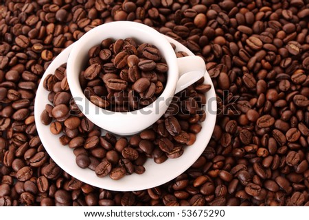 Small white cup of coffee with coffee grain on grain background