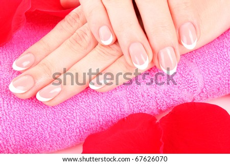 Beaitiful womans hands with manicure on the towel and  rose petals