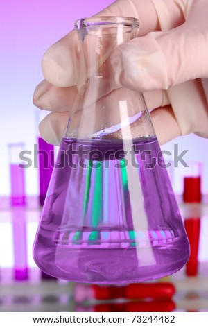 Conical flask with purple liquid on purple background with test-tubes