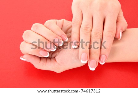 Beautiful woman hands with french manicure on red background