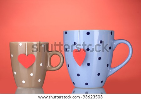 Two cups and tea bags with red heart-shaped label on red background