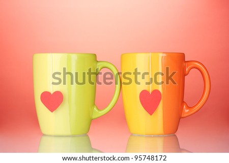 Two cups and tea bags with red heart-shaped label on red background