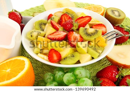 Useful fruit salad of fresh fruits and berries in bowl on napkin isolated on white