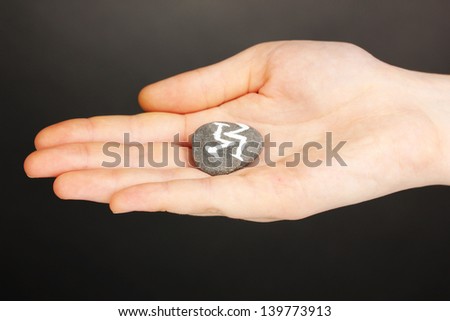 Fortune telling  with symbols on stone in hand on grey background