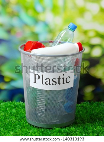 Assorted trash in bucket on nature background