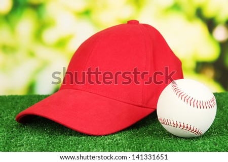 Red peaked cap on grass on natural background