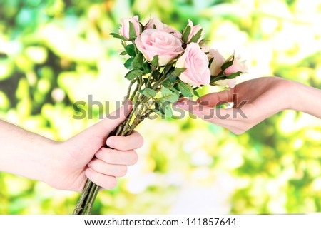 Man\'s hand giving a roses on bright background