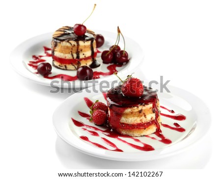 Tasty biscuit cakes with jam and berries on plates, isolated on white