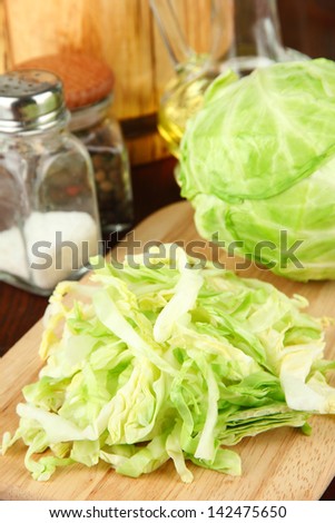 Green cabbage, oil, spices on cutting board, on wooden background