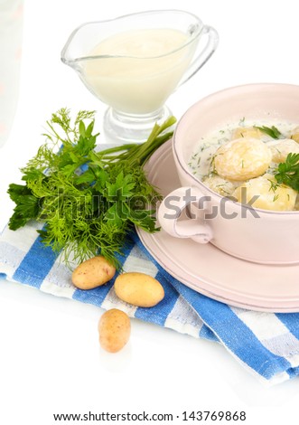 Tender young potatoes with sour cream and herbs in pan isolated on white
