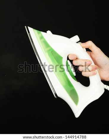 Steam iron in hand, isolated on black