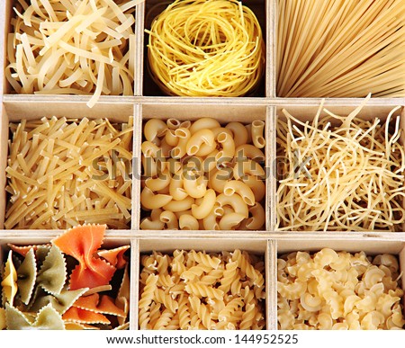 Nine types of pasta in wooden box sections close-up isolated on white