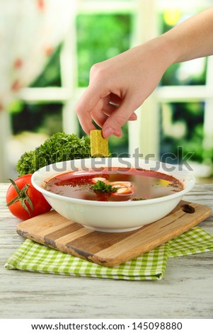 Bowl of soup with bouillon cube on wooden table
