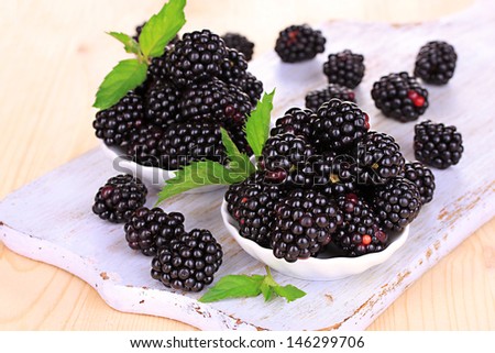 Sweet blackberry in bowls on wooden table