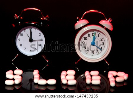 Old style alarm clocks  and pills, on dark background