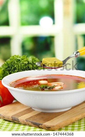 Bowl of soup with bouillon cubes on wooden table