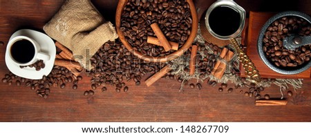 Coffee beans, metal turk and coffee mill on wooden background with copy space