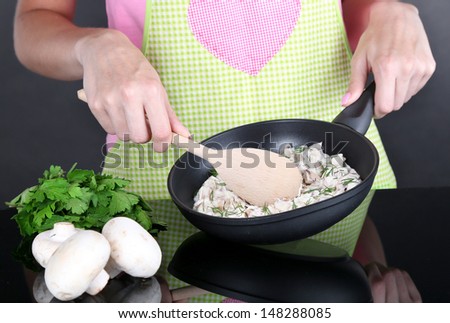 Hands cooking mushroom sauce in pan on gray background