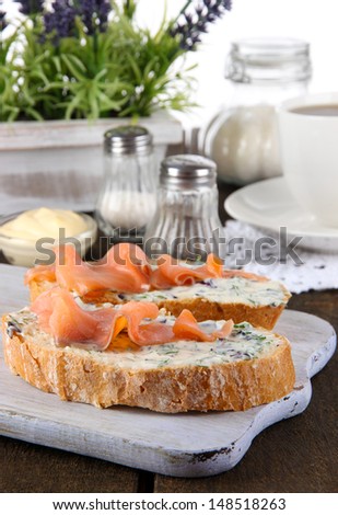 Fish sandwiches and cup of tea on cutting board on wooden table
