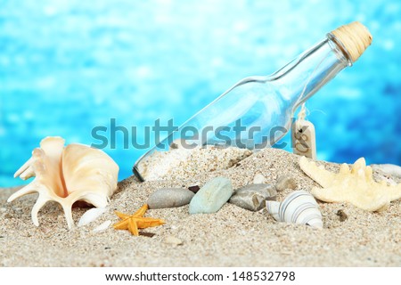 Glass of bottle with note inside on bright blue background