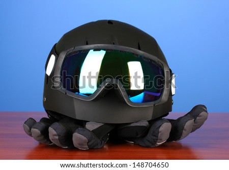 Winter sport glasses, helmet and gloves, on blue background
