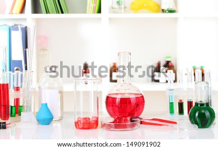 Different laboratory glassware with color liquid on laboratory background