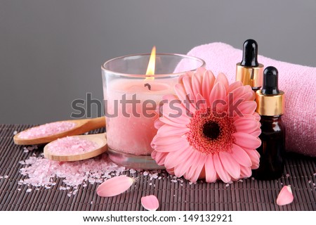 Beautiful pink candle with flower and towel on bamboo mat