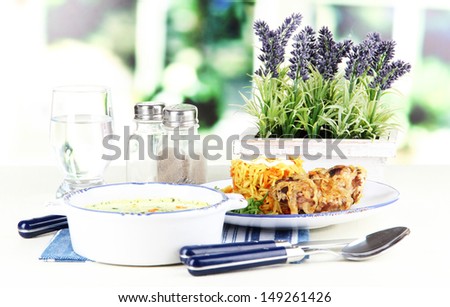Soup and rice with meat in plates on napkin on table on window background