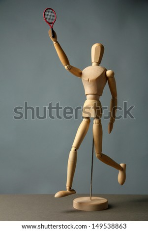 Wooden mannequin with tennis racket on grey background