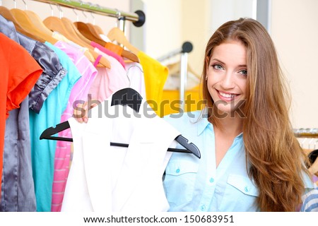 Beautiful girl chooses clothes on room background