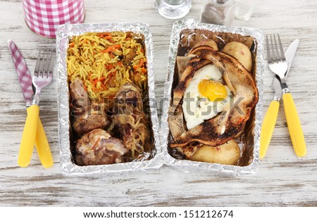 Food in boxes of foil on wooden table