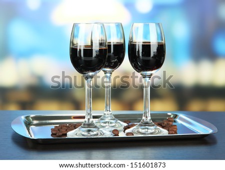 Glasses of liquor on tray,  on bright background