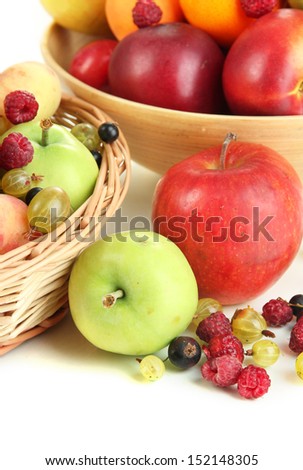 Assortment of juicy fruits in wicker basket and wooden bowl, isolated on white
