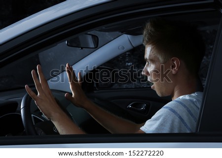 Young man driving in his car at night